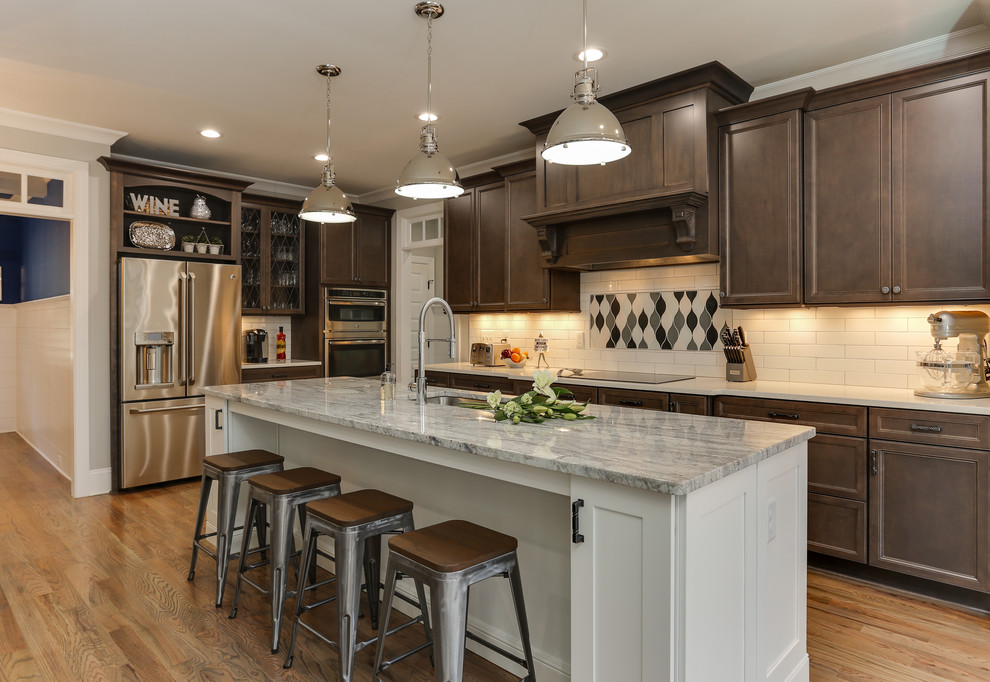 Photo of a mid-sized transitional u-shaped eat-in kitchen in Raleigh with an undermount sink, recessed-panel cabinets, granite benchtops, white splashback, ceramic splashback, stainless steel appliances, with island, dark wood cabinets, light hardwood floors and beige floor.