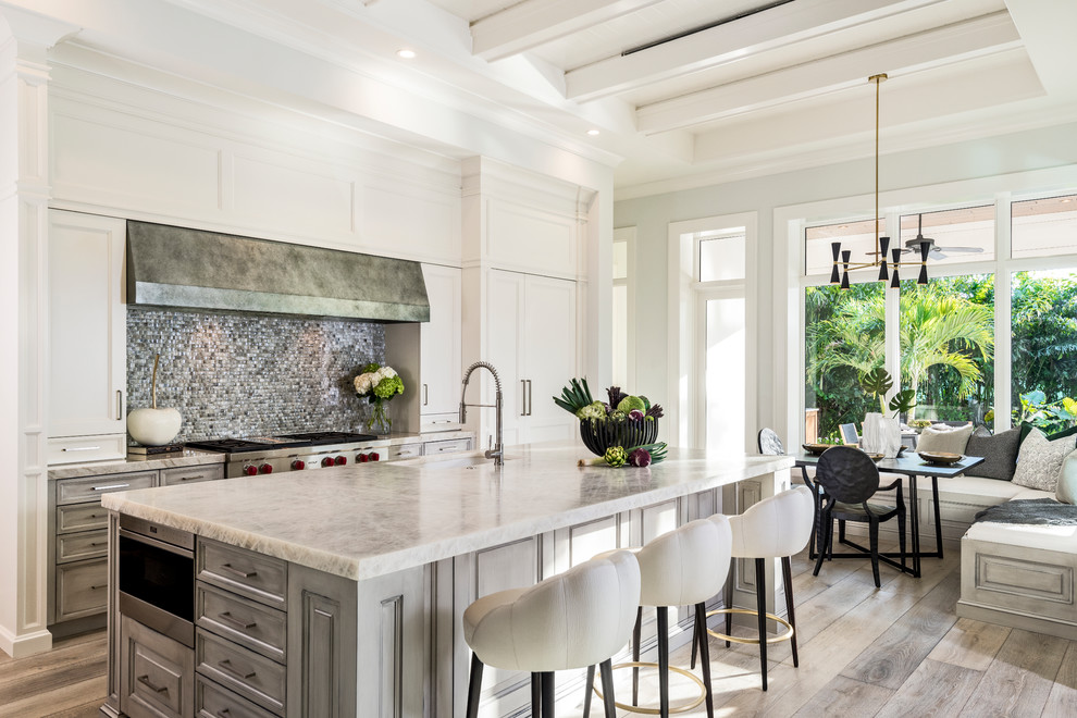 Traditional eat-in kitchen in Other with stainless steel appliances, light hardwood floors, with island, an undermount sink, raised-panel cabinets, grey cabinets, grey splashback and grey floor.
