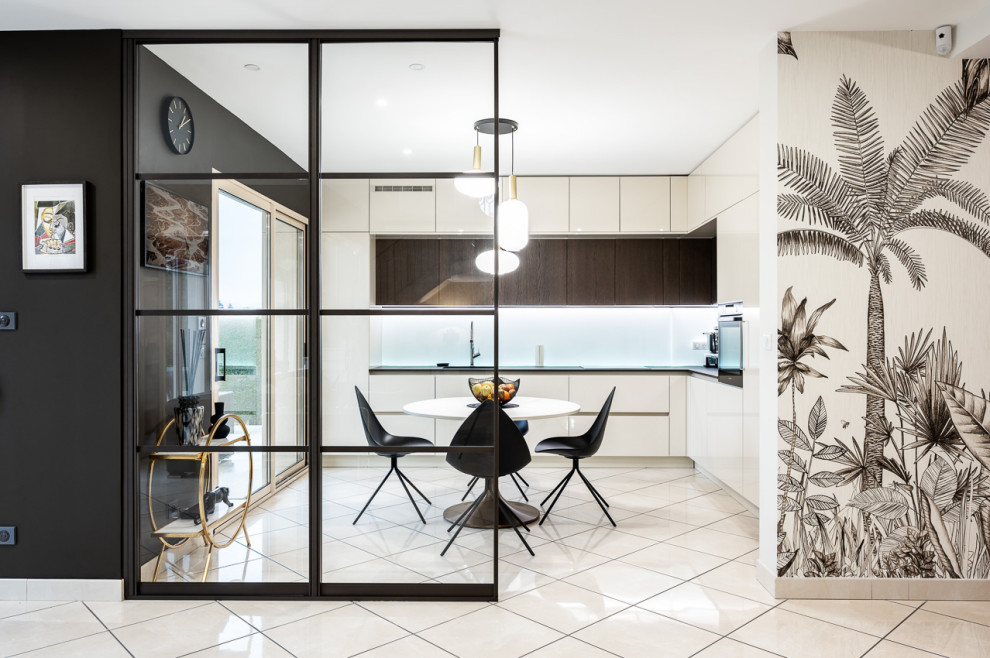 Large contemporary l-shaped open plan kitchen in Lyon with an integrated sink, beaded inset cabinets, white cabinets, solid surface benchtops, white splashback, glass sheet splashback, panelled appliances, marble floors, beige floor and black benchtop.