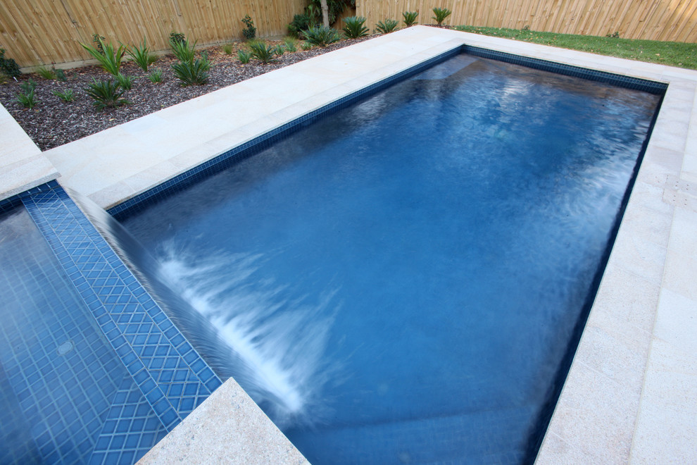 Large beach style backyard rectangular pool in Gold Coast - Tweed with a water feature and natural stone pavers.