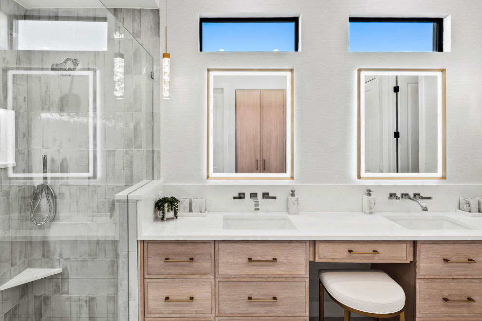 Example of a transitional master gray tile and porcelain tile porcelain tile, white floor and double-sink walk-in shower design with shaker cabinets, light wood cabinets, a two-piece toilet, white walls, an undermount sink, quartz countertops, white countertops, a niche and a built-in vanity