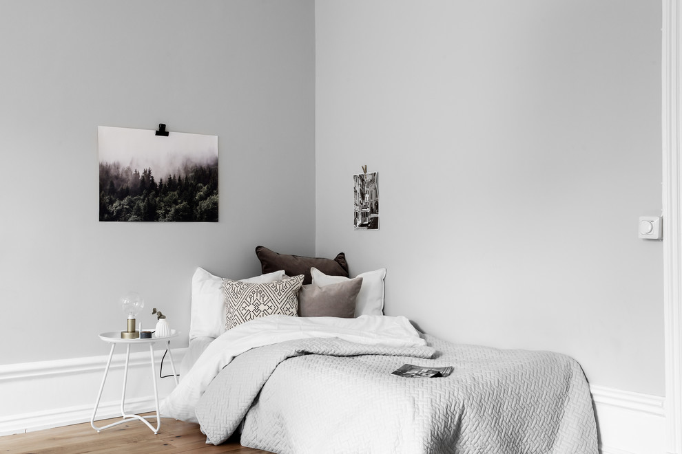 Photo of a mid-sized scandinavian guest bedroom in Stockholm with grey walls and medium hardwood floors.