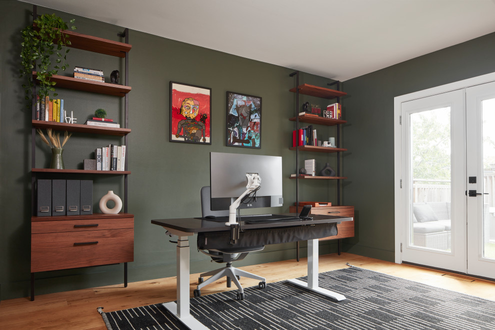 Mittelgroßes Retro Arbeitszimmer mit Arbeitsplatz, grüner Wandfarbe, hellem Holzboden, freistehendem Schreibtisch, beigem Boden und Tapetenwänden in Toronto