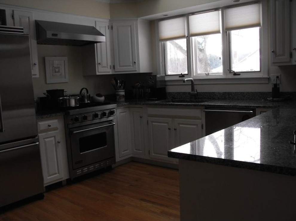 Mid-sized transitional u-shaped light wood floor kitchen photo in Boston with a drop-in sink, raised-panel cabinets, white cabinets, granite countertops and stainless steel appliances