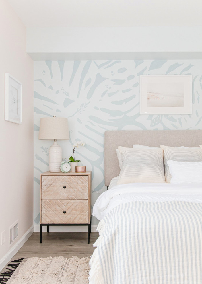 Photo of a mid-sized beach style guest bedroom in Los Angeles with blue walls, light hardwood floors, brown floor and wallpaper.