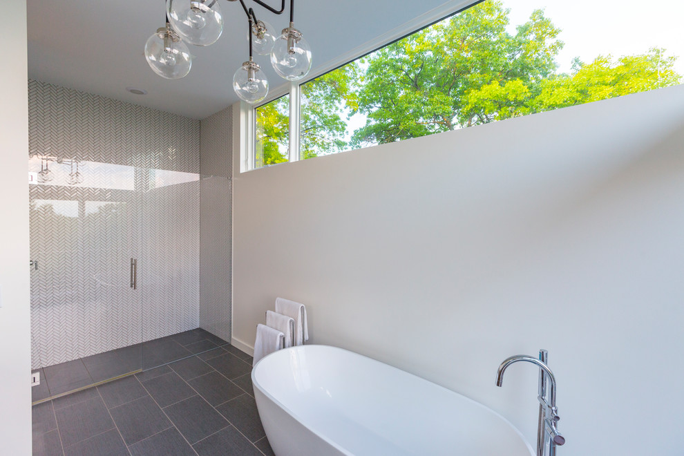 Photo of a modern bathroom in Cincinnati with a freestanding tub, a curbless shower, white walls, porcelain floors, grey floor and a hinged shower door.