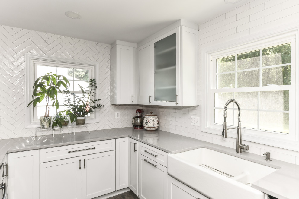 Idéer för att renovera ett stort funkis grå grått kök, med en rustik diskho, skåp i shakerstil, vita skåp, bänkskiva i kvartsit, vitt stänkskydd, stänkskydd i porslinskakel, rostfria vitvaror, vinylgolv, en köksö och brunt golv