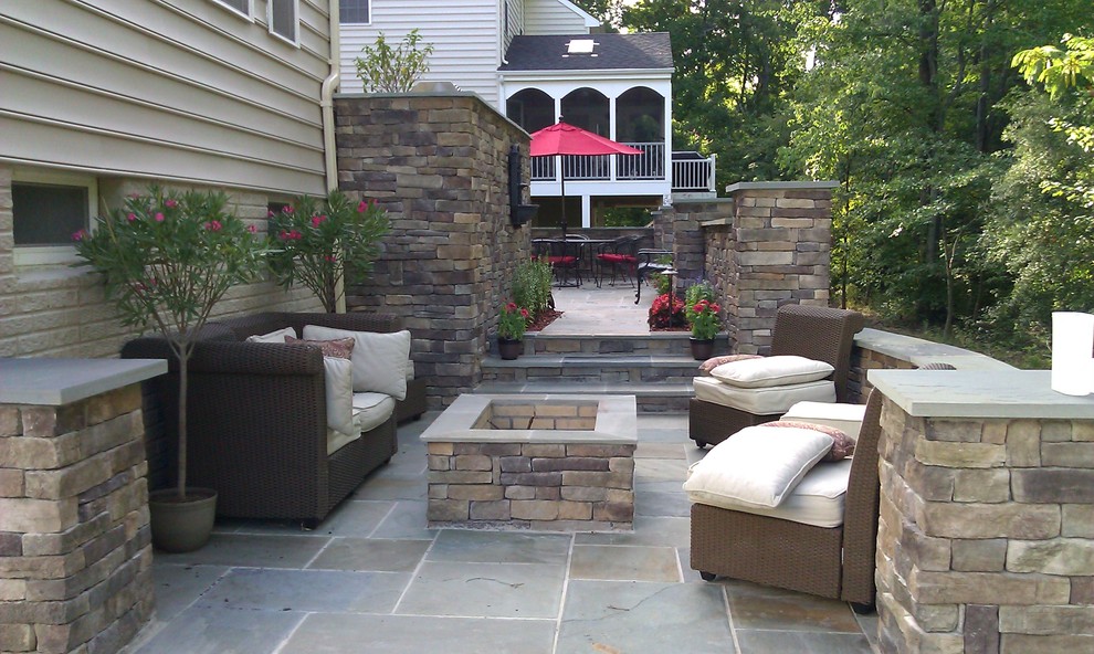 Example of a large transitional backyard stone patio design in DC Metro with a fire pit and no cover