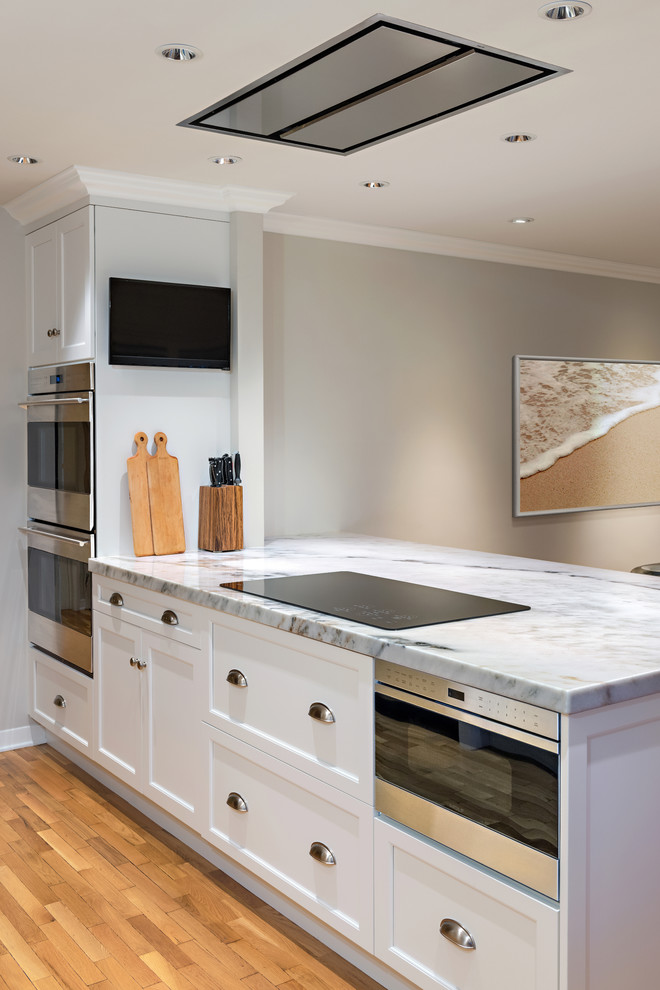 Enclosed kitchen - mid-sized transitional single-wall medium tone wood floor enclosed kitchen idea in Phoenix with an undermount sink, shaker cabinets, white cabinets, marble countertops, gray backsplash, subway tile backsplash, stainless steel appliances and an island