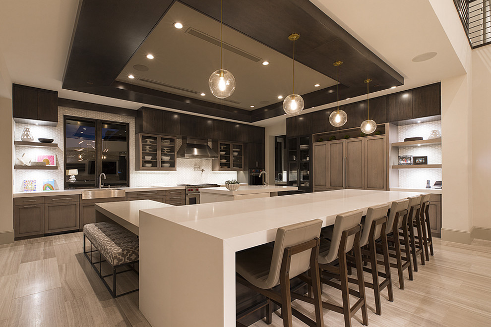 This is an example of an expansive contemporary l-shaped open plan kitchen in Las Vegas with a farmhouse sink, recessed-panel cabinets, stainless steel appliances, multiple islands, solid surface benchtops, white benchtop and recessed.