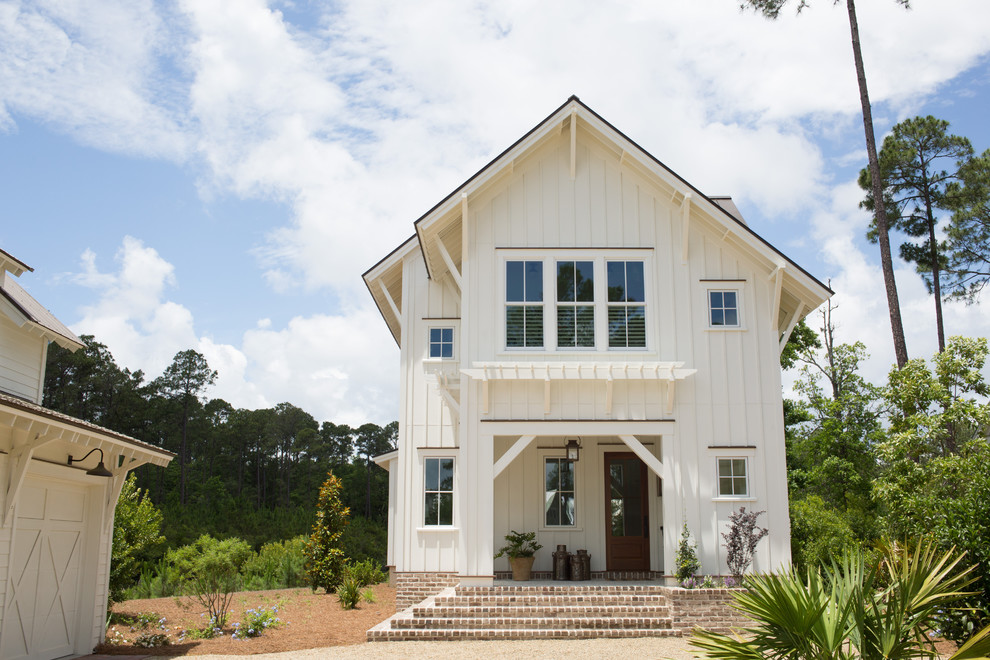 Modelo de fachada de casa blanca de estilo de casa de campo de tamaño medio de dos plantas con revestimiento de aglomerado de cemento, tejado a dos aguas y tejado de metal