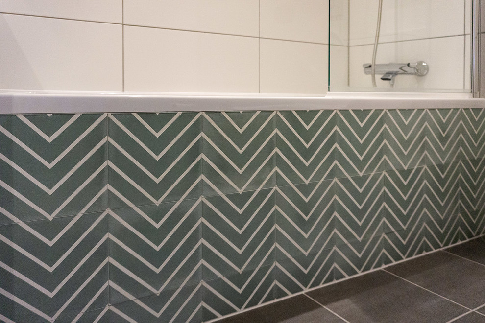 Photo of a small scandinavian bathroom in Berlin with a drop-in tub, green tile, ceramic tile, ceramic floors and grey floor.