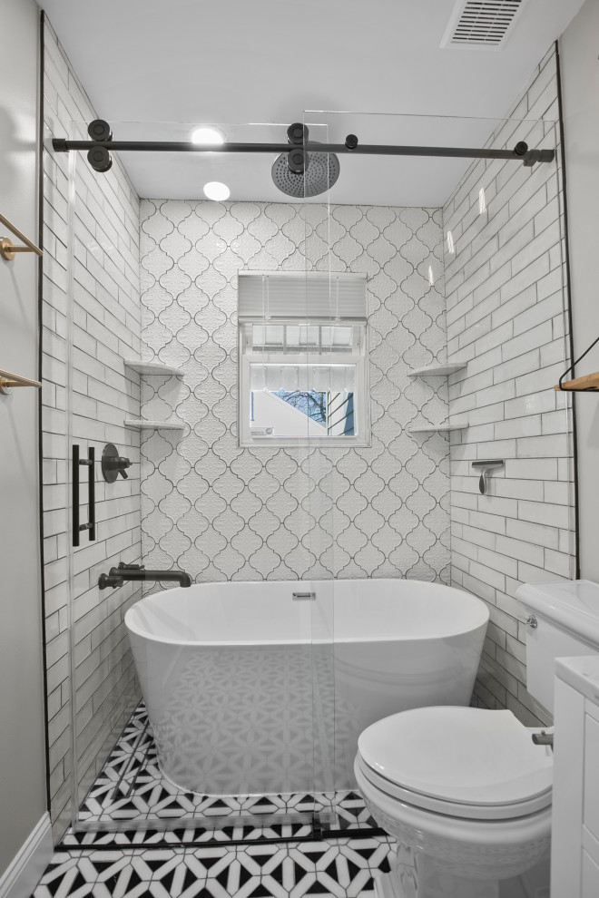 60 tals inredning av ett litet grå grått en-suite badrum, med släta luckor, vita skåp, ett fristående badkar, en dusch/badkar-kombination, en toalettstol med hel cisternkåpa, vit kakel, keramikplattor, grå väggar, mellanmörkt trägolv, ett nedsänkt handfat, bänkskiva i kvarts, brunt golv och dusch med skjutdörr