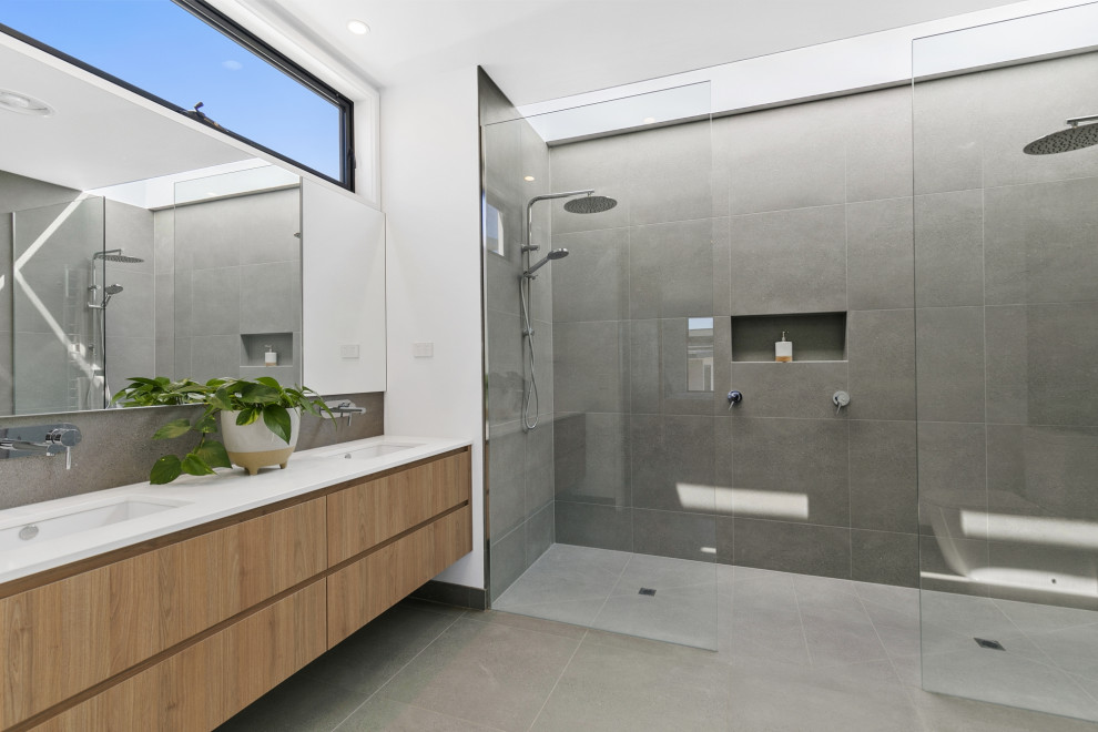 Inspiration for a mid-sized contemporary master bathroom in Geelong with flat-panel cabinets, light wood cabinets, a double shower, gray tile, porcelain tile, porcelain floors, a drop-in sink, solid surface benchtops, grey floor, an open shower and white benchtops.