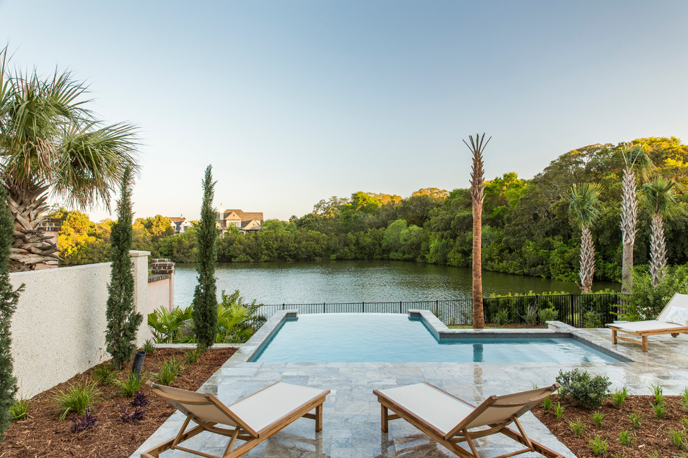 Design ideas for a small traditional backyard l-shaped infinity pool in Charleston with natural stone pavers.