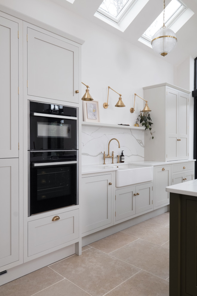Inspiration for a large traditional single-wall open plan kitchen in Cardiff with a farmhouse sink, shaker cabinets, light wood cabinets, quartzite benchtops, white splashback, stone slab splashback, stainless steel appliances, porcelain floors, with island, white benchtop and vaulted.