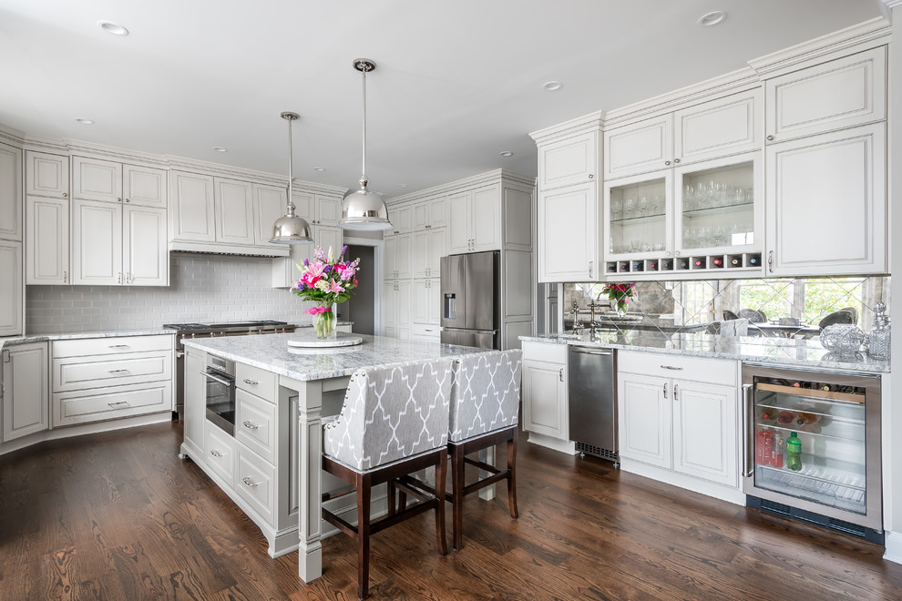 Inspiration for a traditional u-shaped kitchen in Atlanta with raised-panel cabinets, white cabinets, grey splashback, subway tile splashback, stainless steel appliances, dark hardwood floors, with island and brown floor.