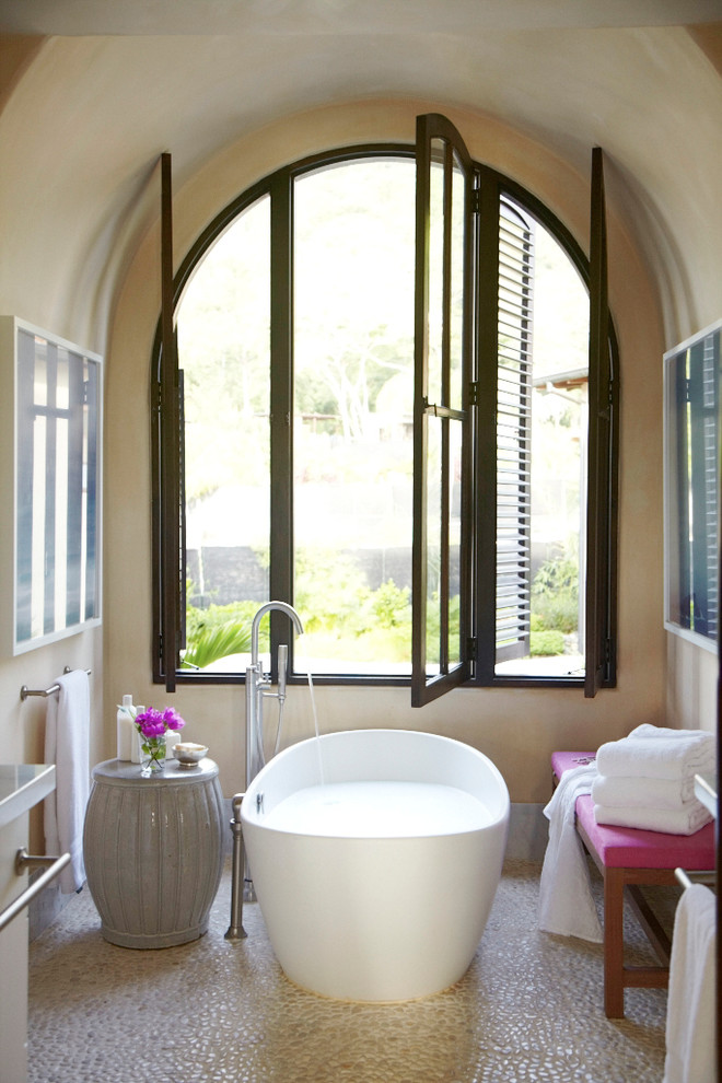 This is an example of a mediterranean master bathroom in Other with a freestanding tub and beige walls.