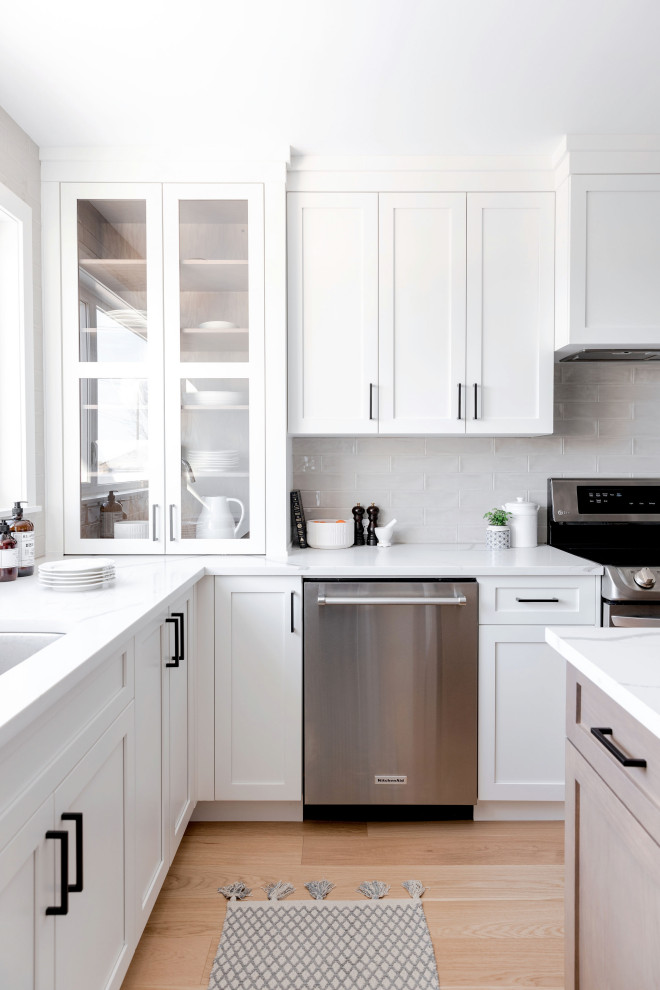 Große Moderne Wohnküche in L-Form mit Schrankfronten im Shaker-Stil, weißen Schränken, Marmor-Arbeitsplatte, Küchenrückwand in Weiß, Kücheninsel und weißer Arbeitsplatte in Calgary