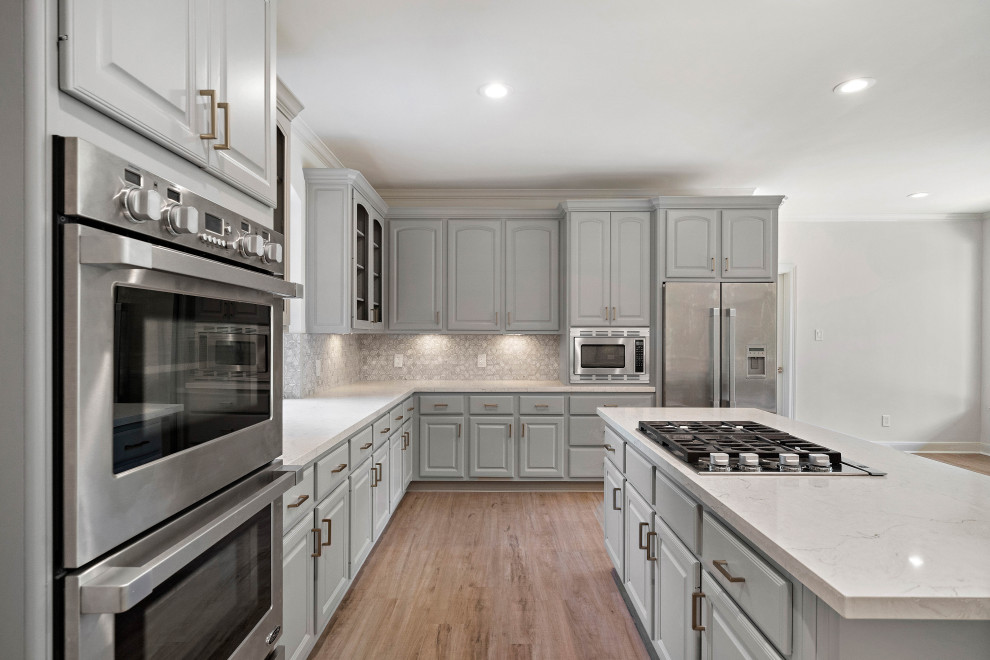 Mid-sized transitional u-shaped light wood floor and brown floor eat-in kitchen photo in Houston with raised-panel cabinets, gray cabinets, white backsplash, marble backsplash, stainless steel appliances, an island, white countertops and quartz countertops