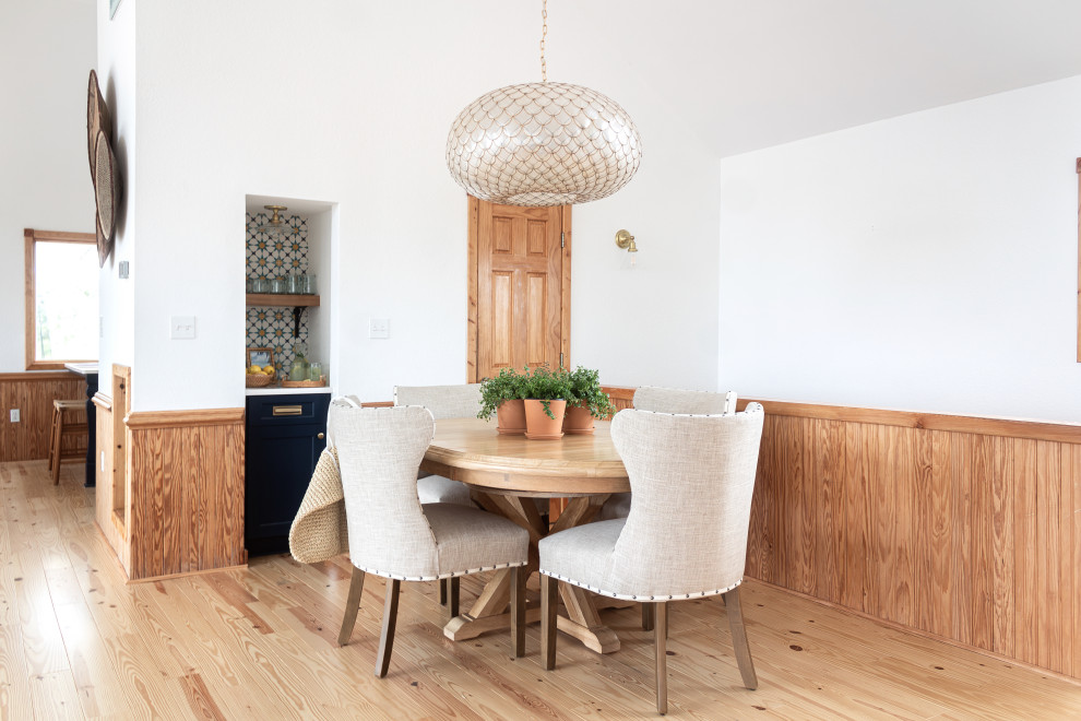 Idée de décoration pour une salle à manger ouverte sur le salon marine de taille moyenne avec un mur blanc, un sol en bois brun et un plafond voûté.