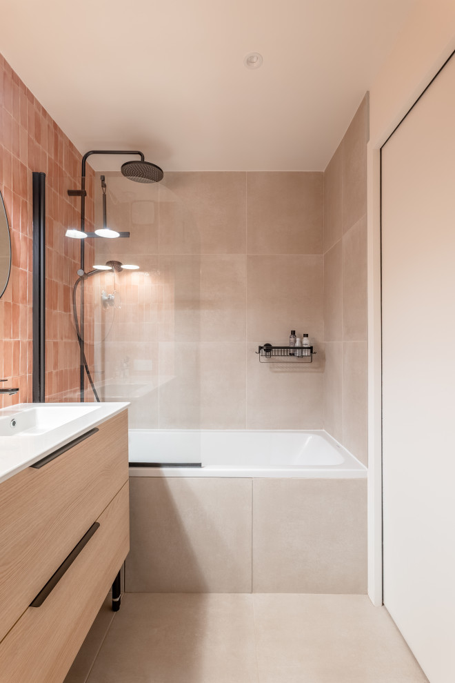 Aménagement d'une salle de bain principale et longue et étroite contemporaine en bois clair de taille moyenne avec un placard à porte affleurante, une baignoire encastrée, un combiné douche/baignoire, WC séparés, un carrelage orange, un carrelage de pierre, un mur blanc, un sol en carrelage de céramique, un lavabo encastré, un sol beige, aucune cabine, un plan de toilette blanc, meuble simple vasque et meuble-lavabo sur pied.