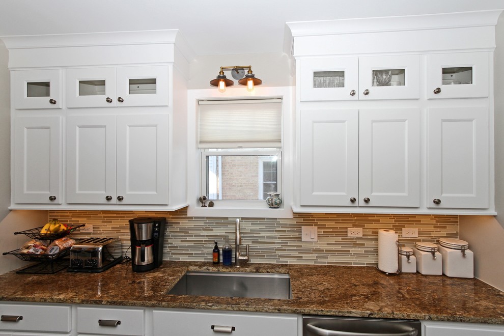 This is an example of a mid-sized transitional galley eat-in kitchen in Chicago with a single-bowl sink, recessed-panel cabinets, white cabinets, granite benchtops, multi-coloured splashback, glass tile splashback, stainless steel appliances, dark hardwood floors, no island and brown floor.