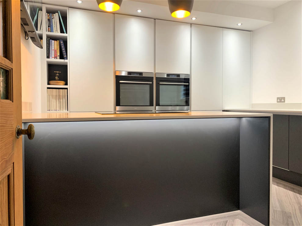 Photo of a small contemporary l-shaped enclosed kitchen in Other with a single-bowl sink, flat-panel cabinets, grey cabinets, quartz worktops, white splashback, black appliances, vinyl flooring, an island and white worktops.