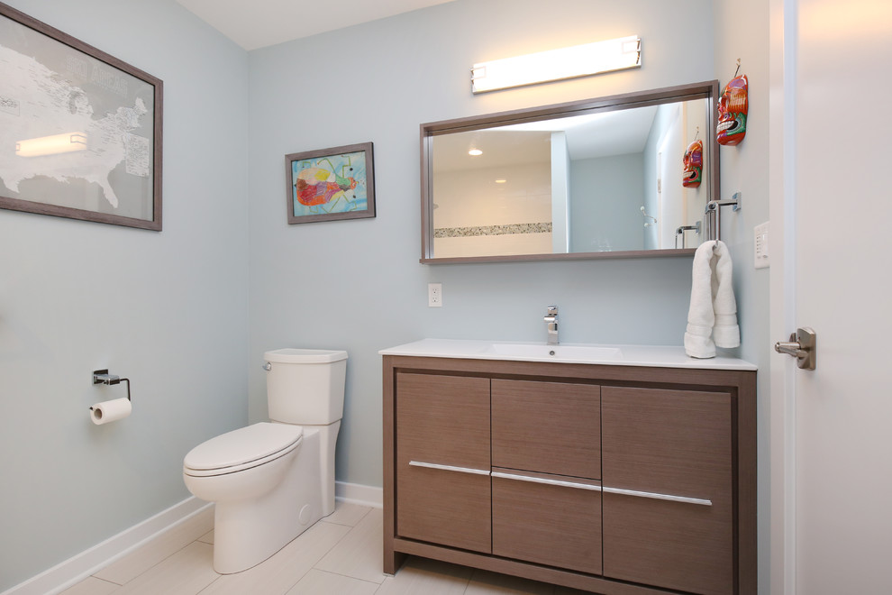 This is an example of a mid-sized modern 3/4 bathroom in Grand Rapids with furniture-like cabinets, light wood cabinets, an alcove tub, a one-piece toilet, white tile, ceramic tile, blue walls, ceramic floors, an integrated sink and engineered quartz benchtops.