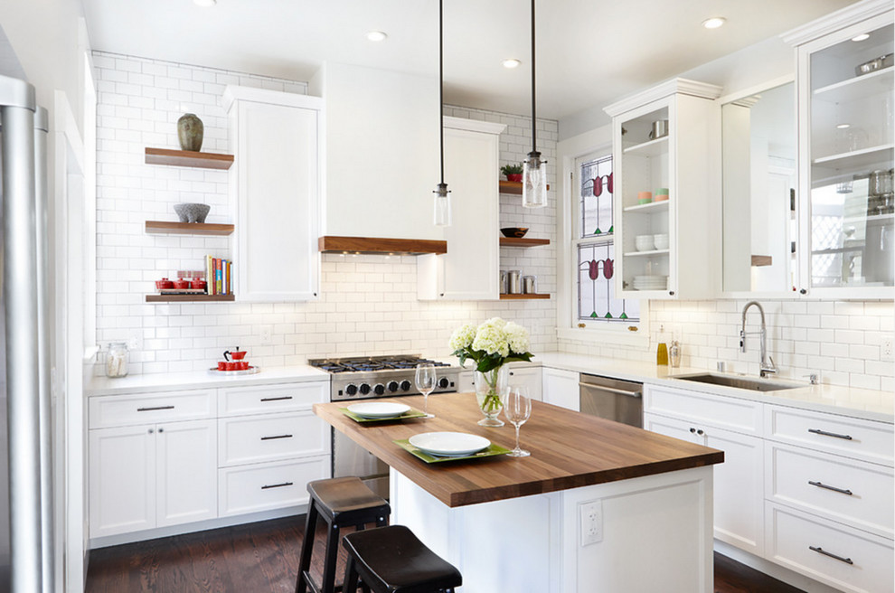 Design ideas for a large transitional l-shaped kitchen in Orange County with an undermount sink, recessed-panel cabinets, white cabinets, white splashback, subway tile splashback, stainless steel appliances, dark hardwood floors, with island, wood benchtops and brown floor.