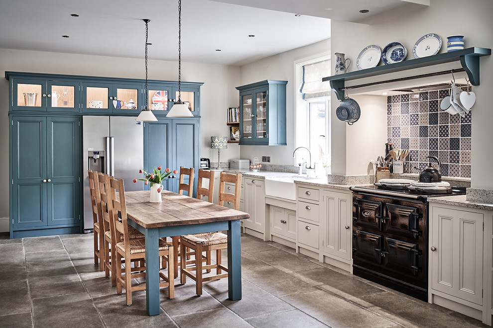This is an example of a large traditional l-shaped eat-in kitchen in Other with a farmhouse sink, beaded inset cabinets, granite benchtops, mosaic tile splashback, ceramic floors, no island, grey benchtop, beige cabinets, multi-coloured splashback, black appliances and grey floor.