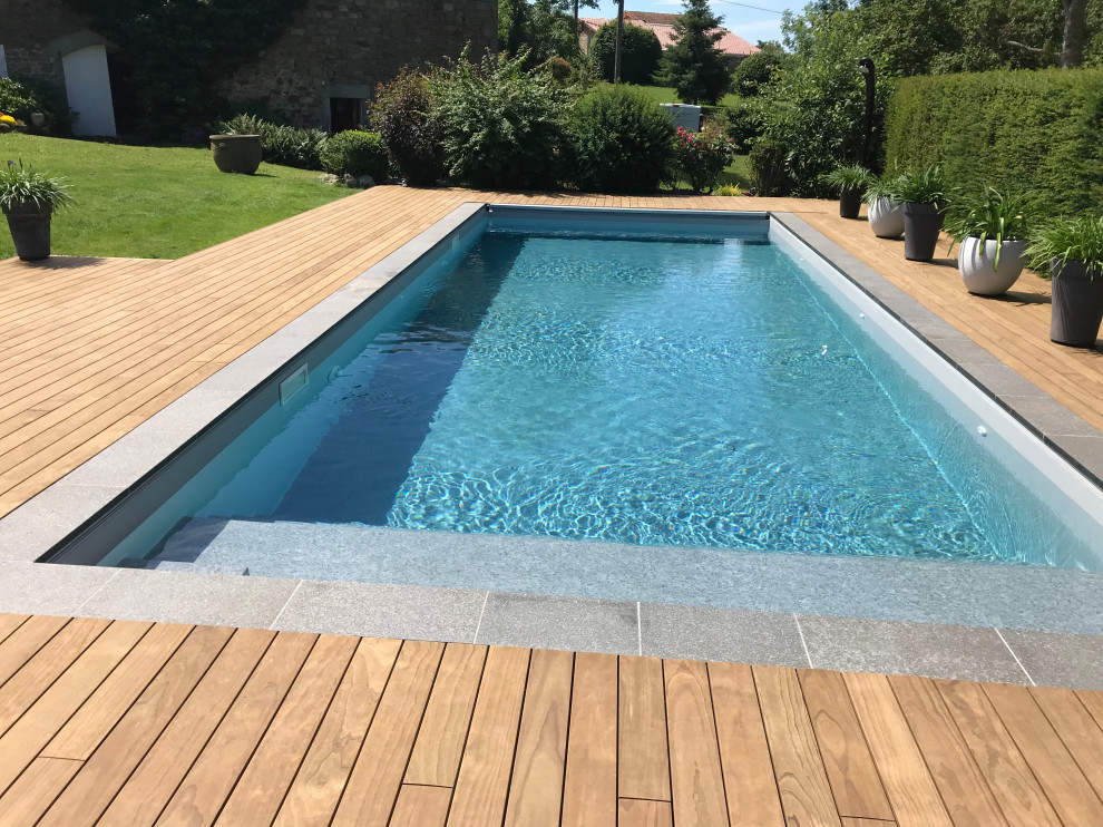 Foto de piscina tradicional renovada rectangular en patio trasero con paisajismo de piscina y entablado