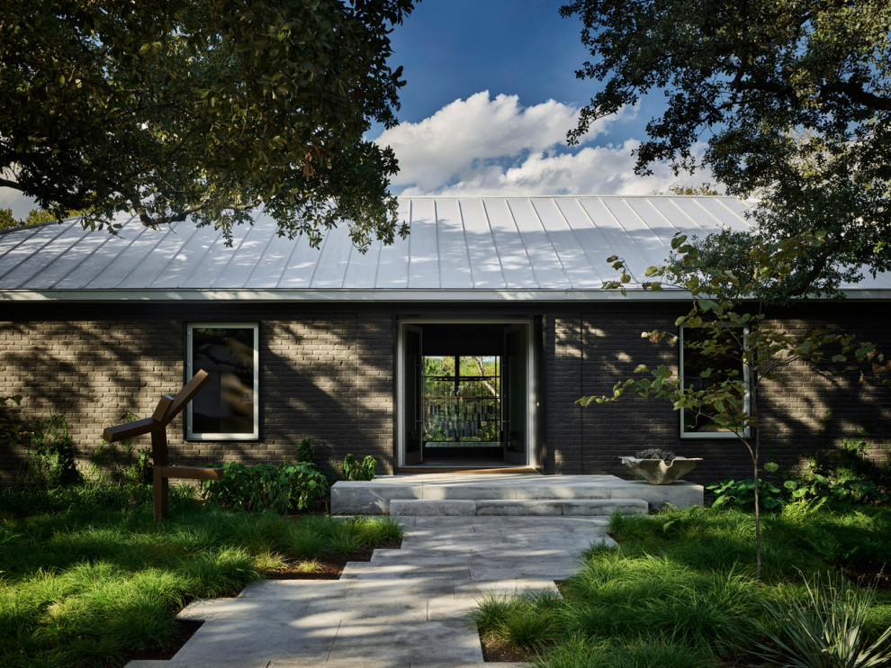 Imagen de fachada de casa gris y gris retro grande de dos plantas con revestimiento de ladrillo y tejado de metal