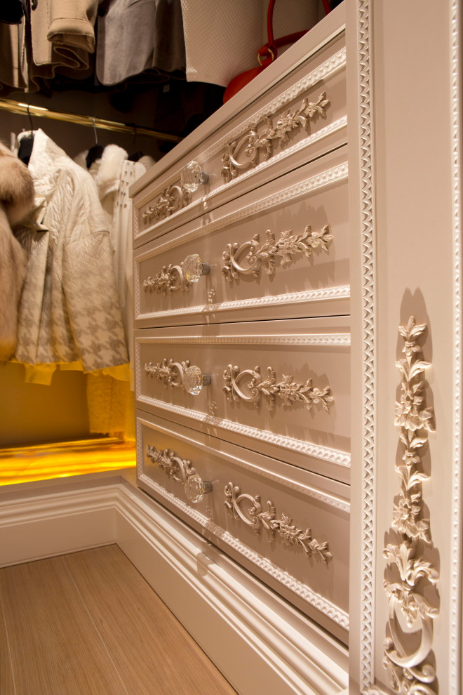 Photo of a large contemporary gender-neutral storage and wardrobe in Other with raised-panel cabinets, white cabinets, light hardwood floors, brown floor and coffered.