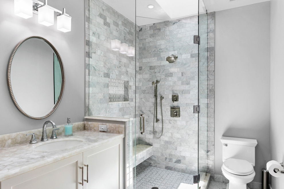 Modern inredning av ett beige beige badrum med dusch, med luckor med upphöjd panel, grå skåp, en toalettstol med hel cisternkåpa, grå kakel, porslinskakel, grå väggar, marmorgolv, ett undermonterad handfat, bänkskiva i kvartsit, vitt golv, dusch med gångjärnsdörr och en hörndusch
