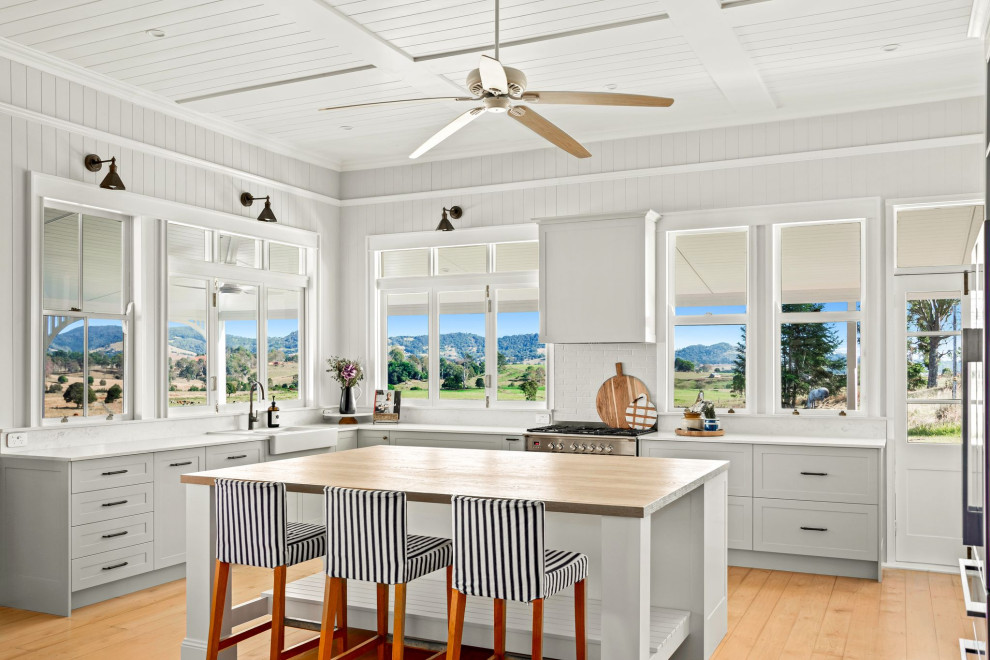 Inspiration for a mid-sized country l-shaped kitchen pantry in Sunshine Coast with a farmhouse sink, shaker cabinets, green cabinets, quartz benchtops, white splashback, engineered quartz splashback, stainless steel appliances, medium hardwood floors, with island, yellow floor, white benchtop and timber.