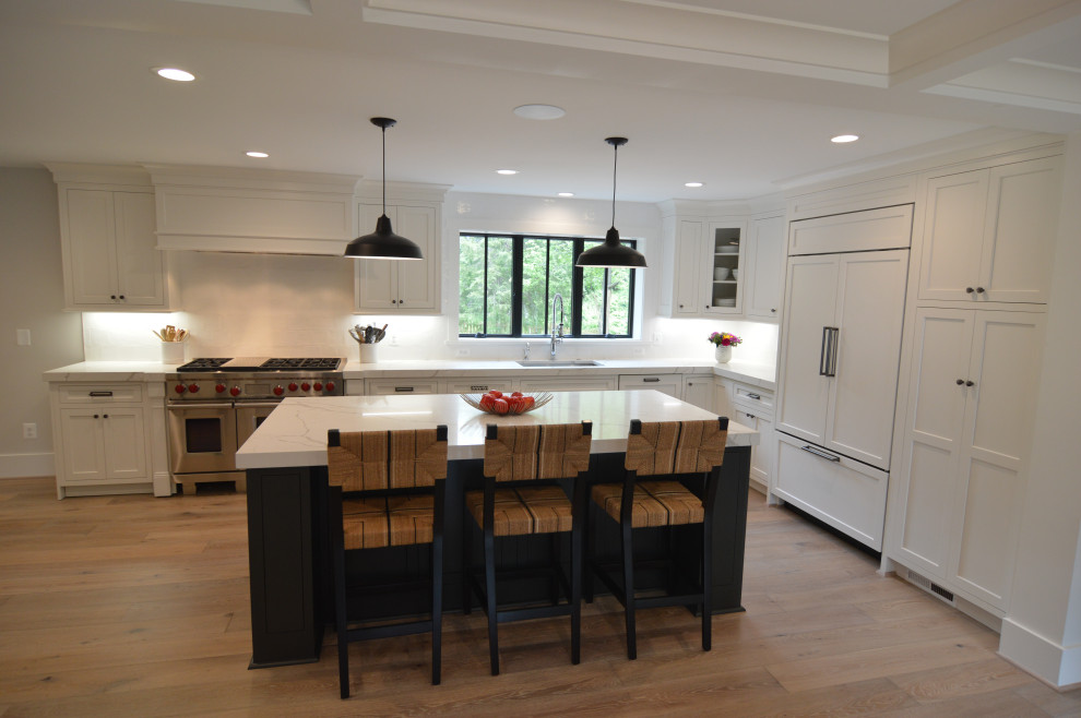 Eat-in kitchen - large transitional l-shaped light wood floor and brown floor eat-in kitchen idea in DC Metro with an undermount sink, recessed-panel cabinets, white cabinets, quartz countertops, white backsplash, ceramic backsplash, paneled appliances, an island and white countertops