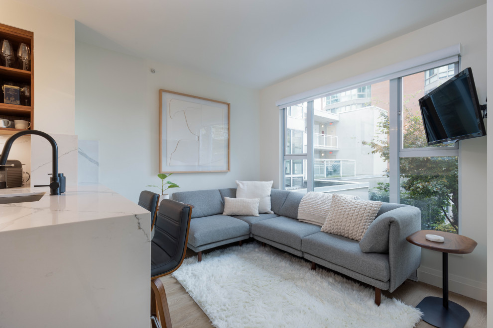 Kleines, Offenes Modernes Wohnzimmer mit Hausbar, weißer Wandfarbe, Laminat, TV-Wand und braunem Boden in Vancouver