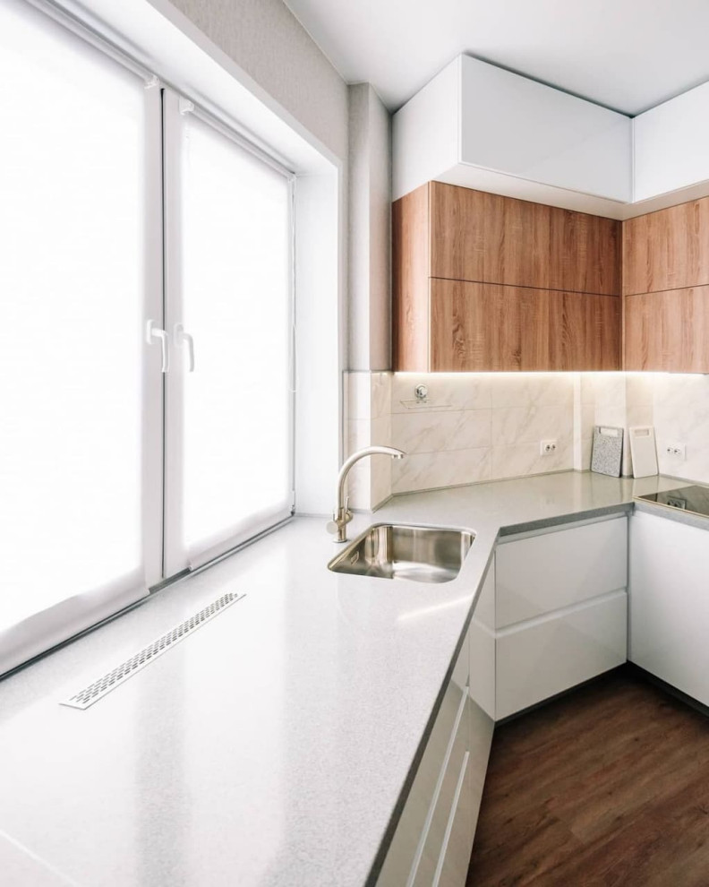 This is an example of a large contemporary u-shaped eat-in kitchen in Novosibirsk with an undermount sink, flat-panel cabinets, white cabinets, solid surface benchtops, white splashback, glass sheet splashback, stainless steel appliances, medium hardwood floors, a peninsula, brown floor and grey benchtop.