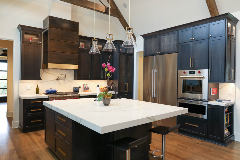 Example of a large transitional u-shaped light wood floor open concept kitchen design with a farmhouse sink, flat-panel cabinets, dark wood cabinets, quartz countertops, white backsplash, quartz backsplash, stainless steel appliances, an island and white countertops