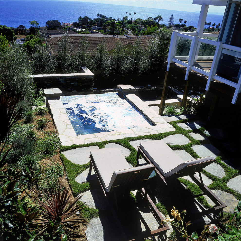 Inspiration for a tropical backyard stone and custom-shaped hot tub remodel in Orange County