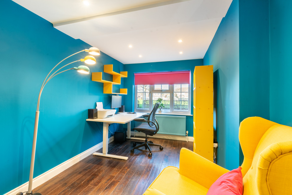 Cette image montre un bureau design de taille moyenne avec un mur bleu, parquet foncé, un bureau indépendant et un sol marron.