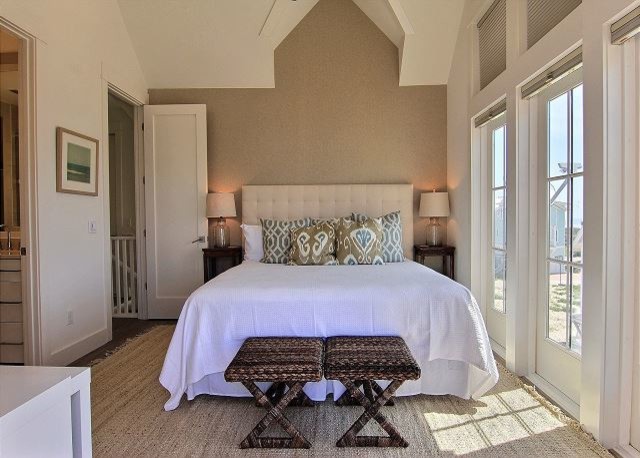 Mid-sized beach style master bedroom in Austin with white walls, medium hardwood floors and brown floor.