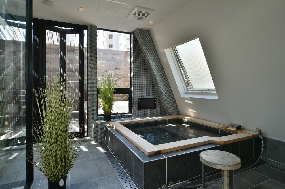 This is an example of an industrial bathroom in Tokyo with a hot tub, black and white tile, white walls, porcelain floors and grey floor.
