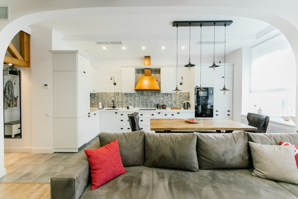 Mid-sized mediterranean l-shaped eat-in kitchen in Moscow with white cabinets, solid surface benchtops, porcelain splashback, black appliances, porcelain floors, grey floor, an undermount sink, recessed-panel cabinets, white splashback and no island.