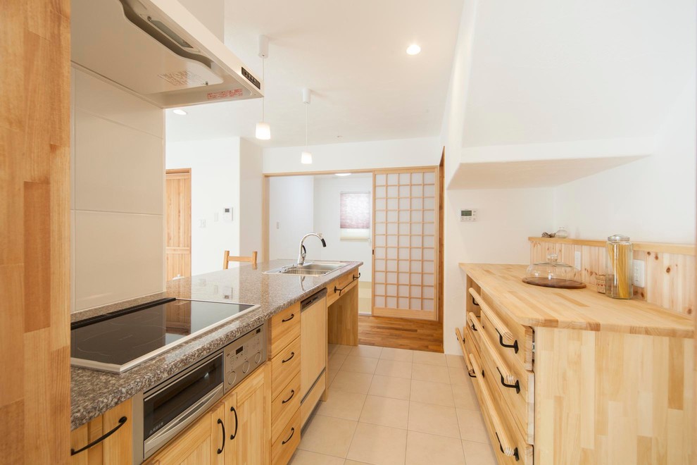 This is an example of a transitional single-wall open plan kitchen in Other with a single-bowl sink, flat-panel cabinets, medium wood cabinets, granite benchtops, white splashback, terra-cotta floors, a peninsula and beige floor.