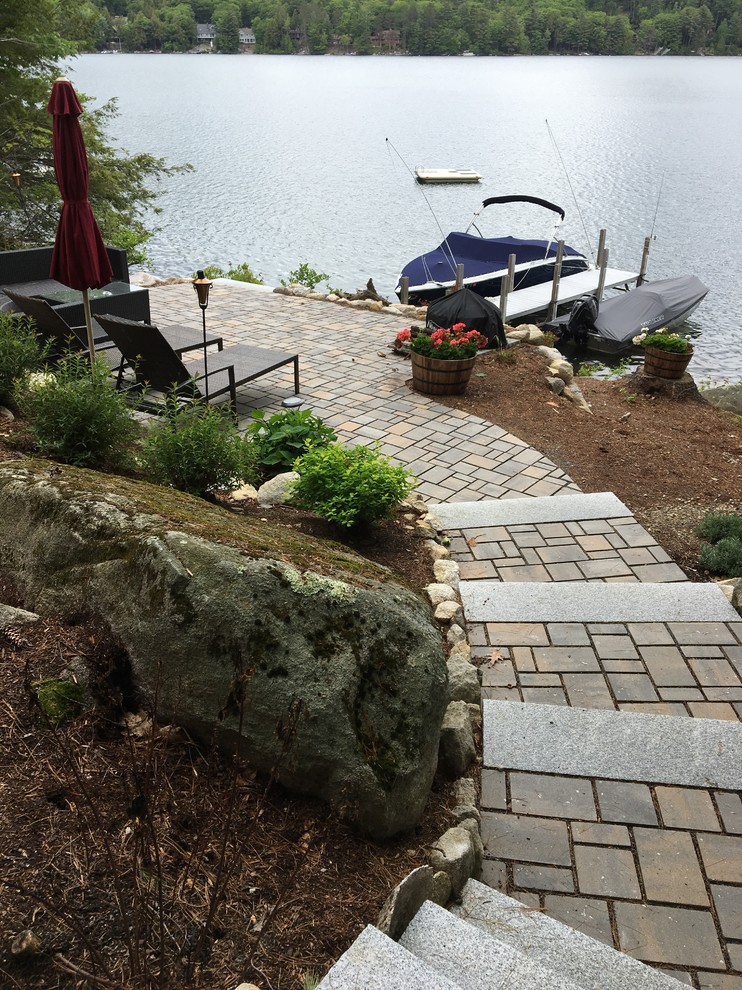Inspiration for a mid-sized beach style backyard full sun xeriscape for summer in Boston with a retaining wall and brick pavers.