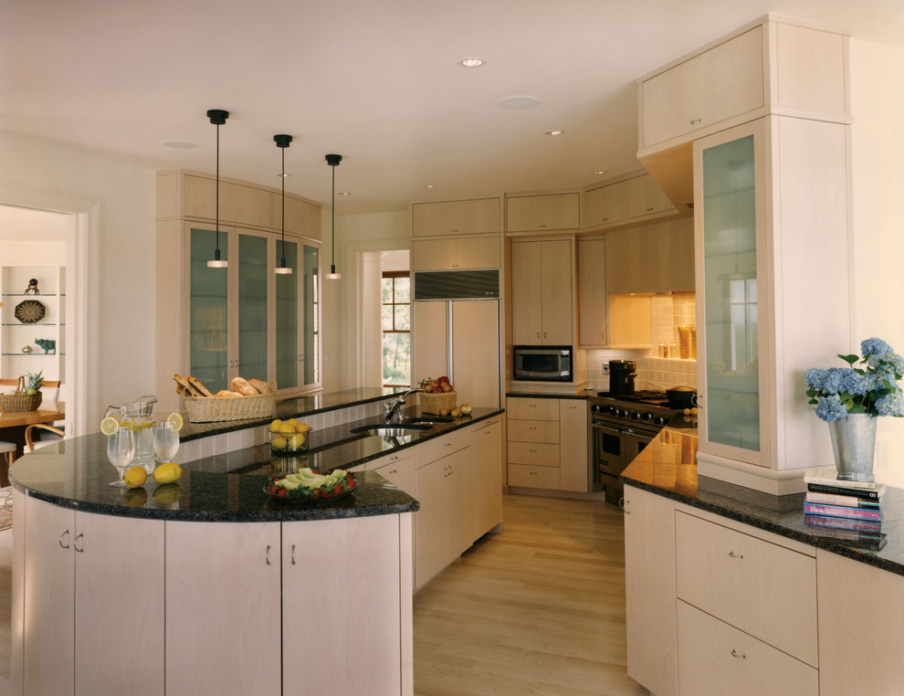 This is an example of a large contemporary u-shaped separate kitchen in Boston with an undermount sink, flat-panel cabinets, light wood cabinets, granite benchtops, stone tile splashback, panelled appliances, light hardwood floors, with island and beige splashback.