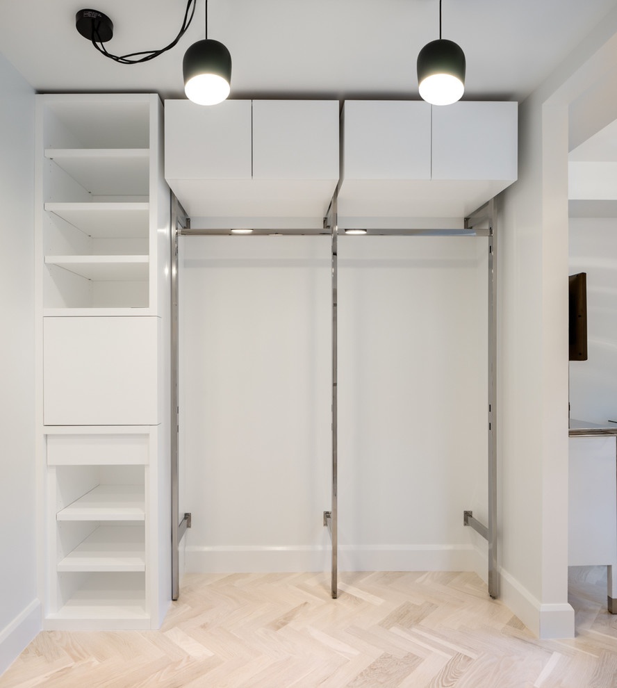 Small traditional gender-neutral built-in wardrobe in Miami with flat-panel cabinets, white cabinets and travertine floors.