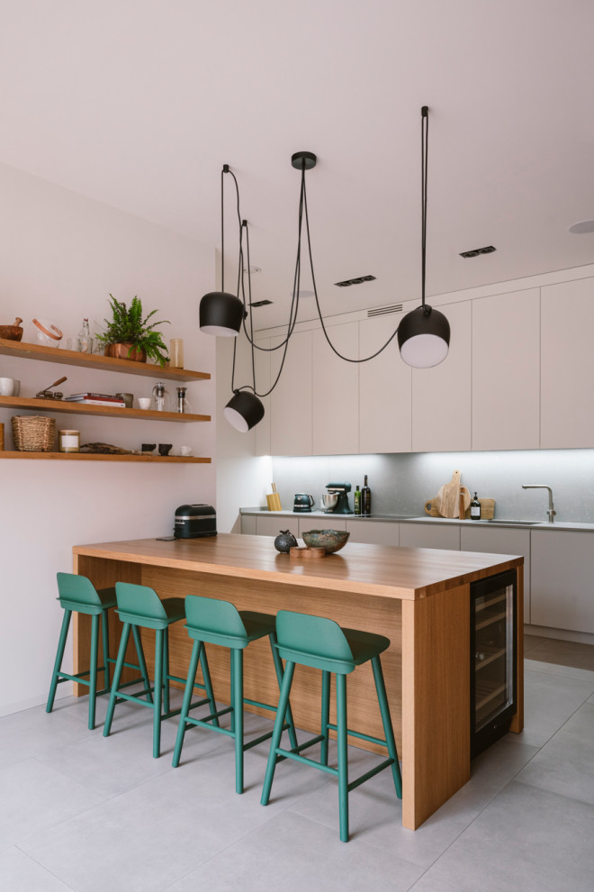 Esempio di una cucina parallela minimal con ante lisce, ante bianche, paraspruzzi grigio, penisola, pavimento grigio e top grigio